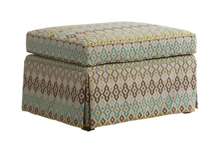 Angled shot of the Tessa ottoman by Vogel with a skirt and a brown and blue fabric cover
