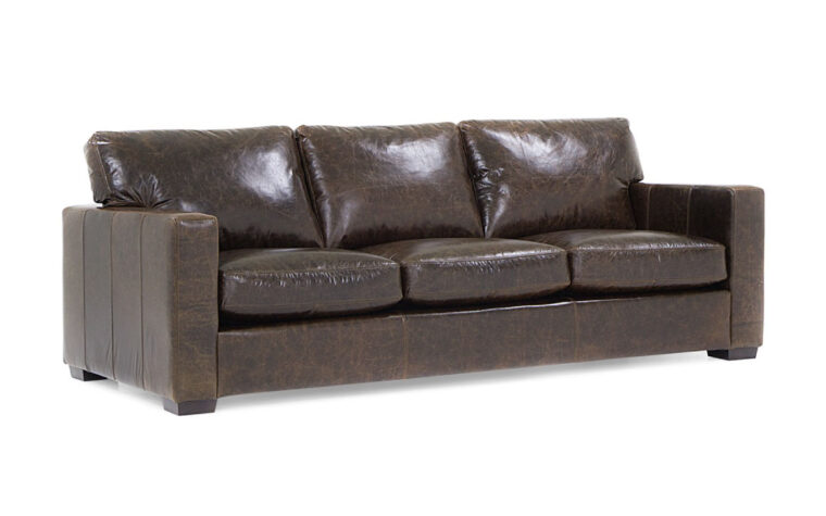 side angle of contemporary brown leather colebrook sofa with three seat cushions and dark brown wood legs