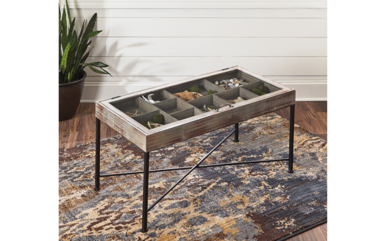 shellmond cocktail table is finished in an anitque grey finish and accented with black legs. It features a top that opens and you can store thigns under the glass top.