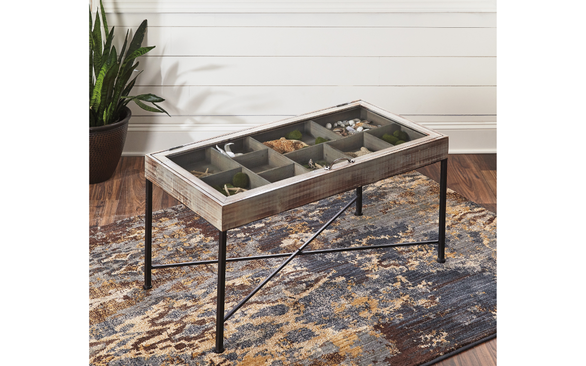 shellmond cocktail table is finished in an anitque grey finish and accented with black legs. It features a top that opens and you can store thigns under the glass top.