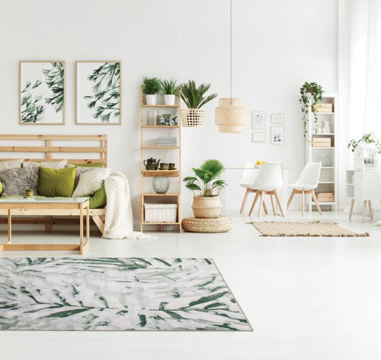 Antika II Area Rug by Kalora - palm branch pattern overlaid on cream background - rug on white floor with Scandinavian wooden furniture and decor
