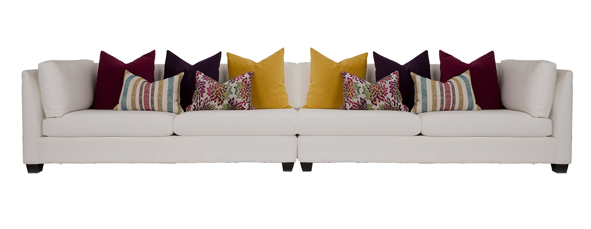 2875 Sectional by Decor-Rest upholstered in an off-white fabric with dark legs and lots of toss cushions in a variety of summery colours (mustard, burgundy, green)