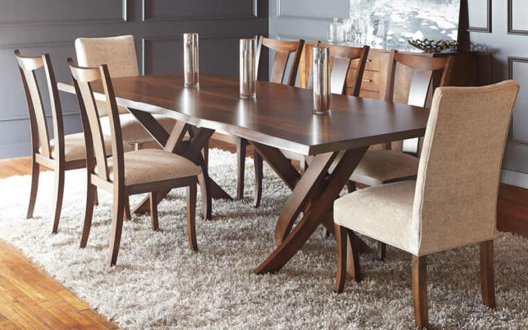 Live Edge Table by Bertanie - swirling leg structure supporting wooden table with live edge feature; situated on a cream rug in a dining room with upholstered side and head chairs in cream fabric and warm wood tones
