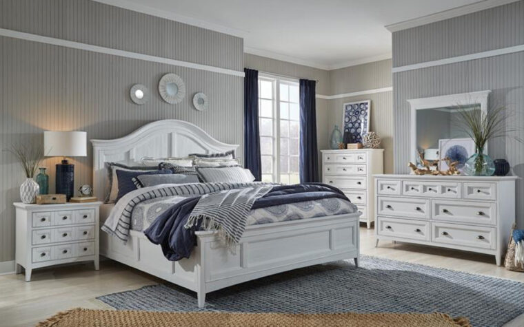 B4400 Heron Cove Bedroom Collection - Universal Furniture - relaxed casual bedroom furniture finished in Chalk White; arched headboard pairs with paneled footboard and 2 drawer chests and a nightstand in a bedroom featuring grey wallpaper, an off-grey wooden floor, and a grey area rug, white navy curtains and bedding