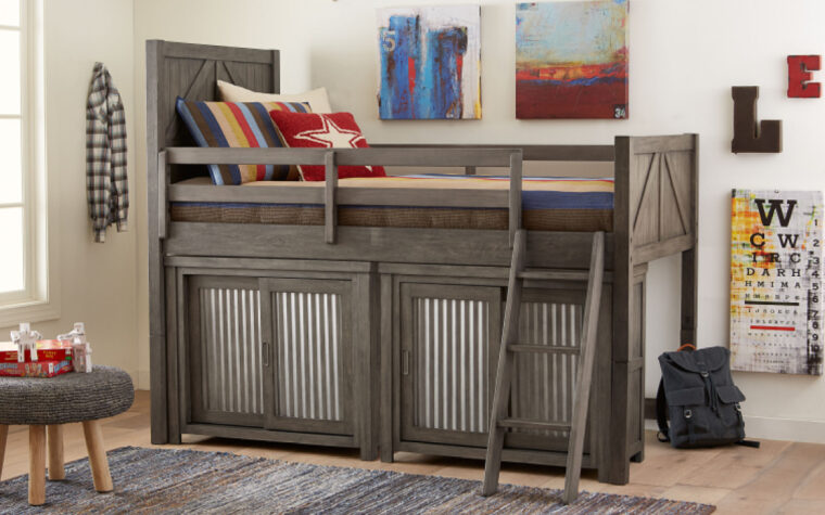 2 Bunkhouse Sliding Door Chests positioned under the Loft Bed; staged on a wooden floor next to an area rug and made up with red, blue and yellow bedding in a fun, kid-ish style
