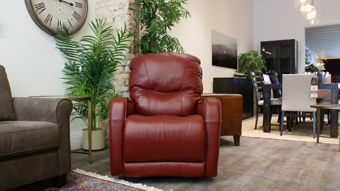 Palliser recliner upholstered in red leather; perfect for petite individuals; displayed against greenery in Chervin Furniture & Design showroom