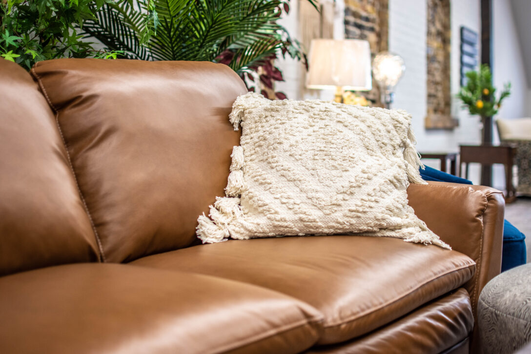 Brown leather sofa (close-up) with white throw pillow (Renwil) in Elmira showroom of Chervin Furniture & Design