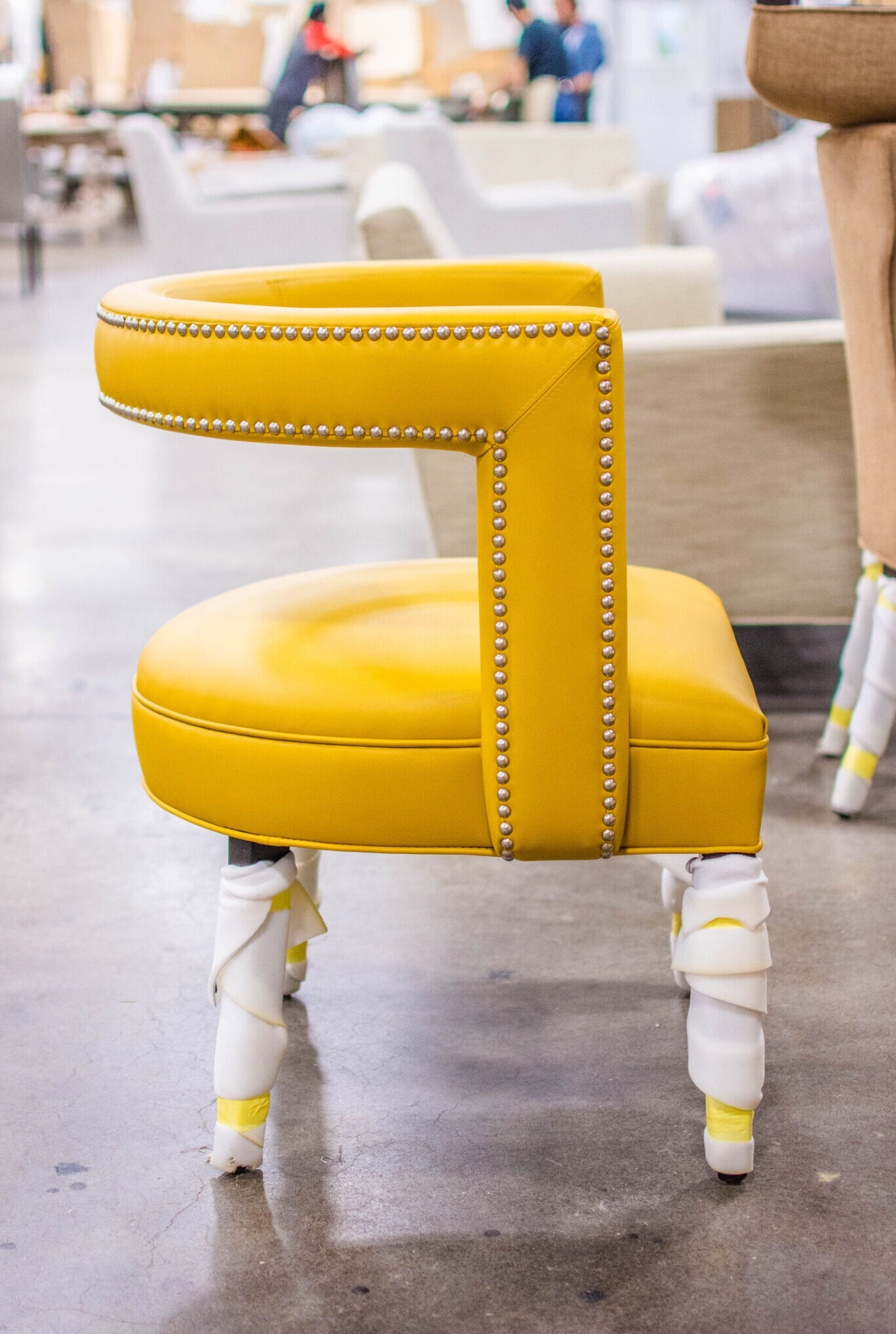 Vogel accent chair in production - featuring nail head trim on vibrant yellow leather