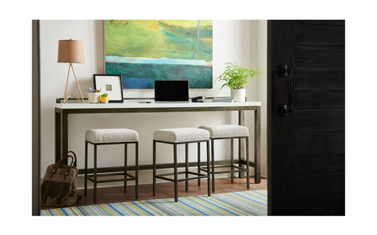 Console table with three upholstered stools against a wall