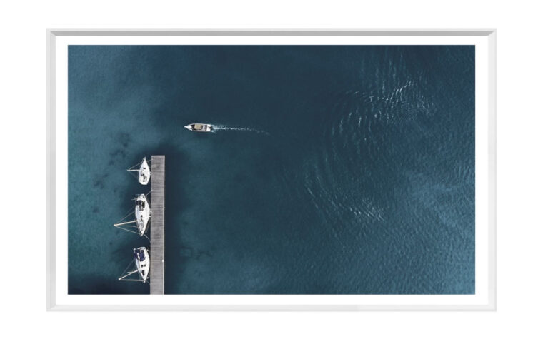 artwork featuring three yachts are tied to a boating dock on a deep blue body of water with a boat drives by