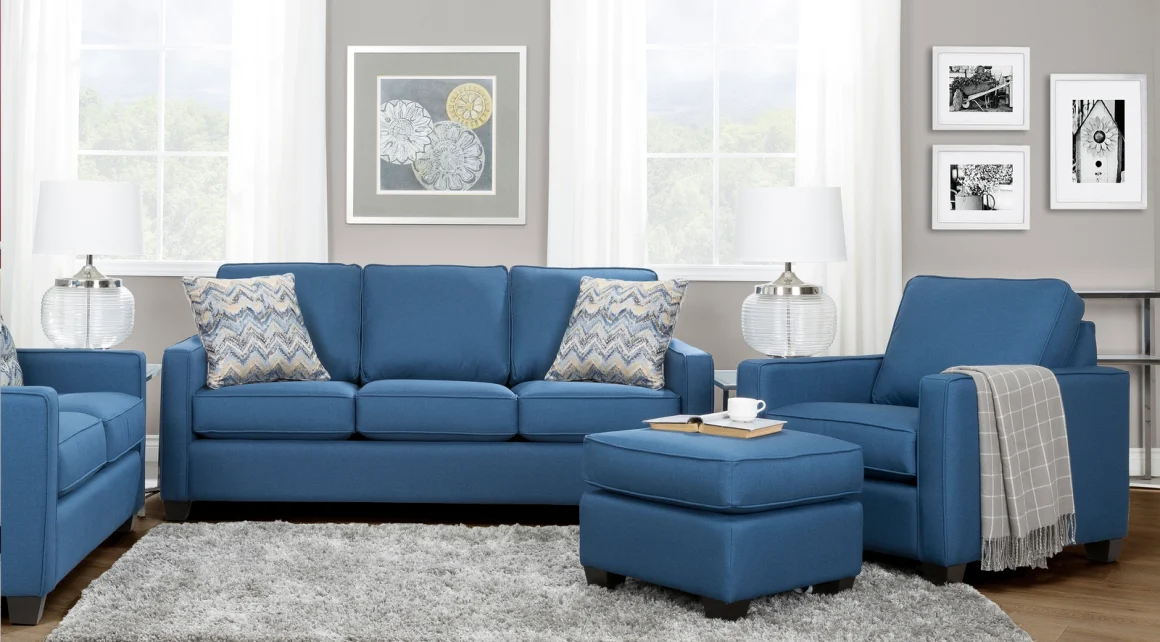 A living room setting with blue sofa, loveseat, and chair with ottoman. 