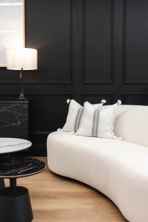 A modern curved sofa in a creamy white fabric with accent pillows.