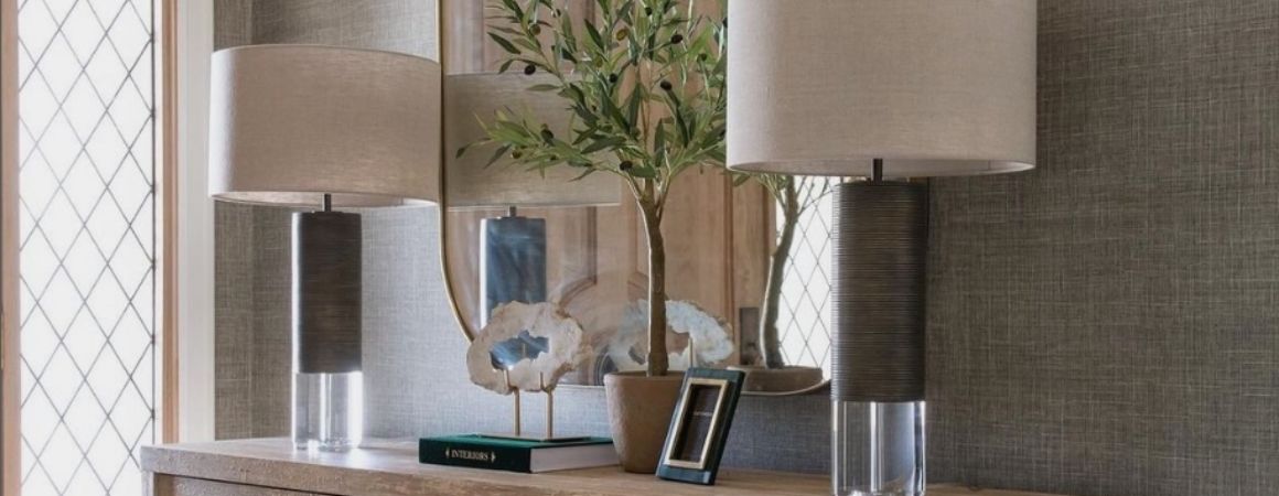 Modern FlowDecor lamps with glass and bronze bases and beige linen shades displayed on a sideboard with additional decor