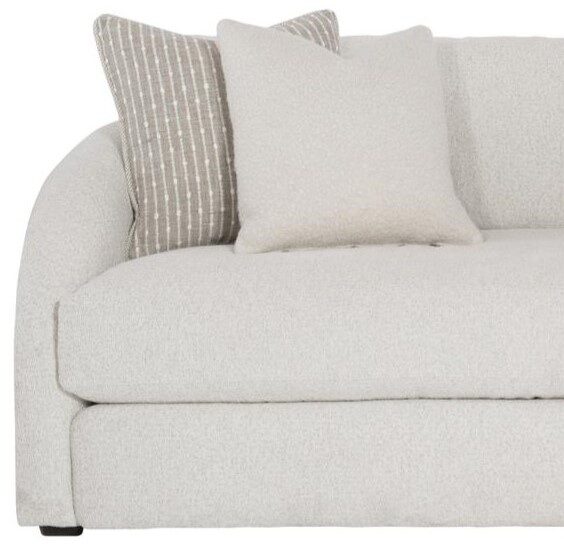 A contemporary curved sofa detail shot showcasing the sofa end and throw pillows