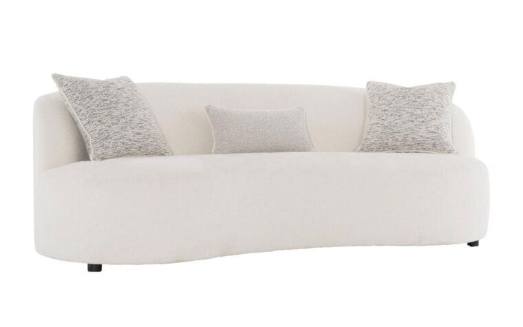 The Elle modern curved sofa from Bernhardt in a cream boucle fabric with three speckled beige throw pillows and dark wood feet