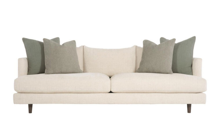 The stylish modern Colette sofa by Bernhardt in cream fabric with two green throw pillows on either side