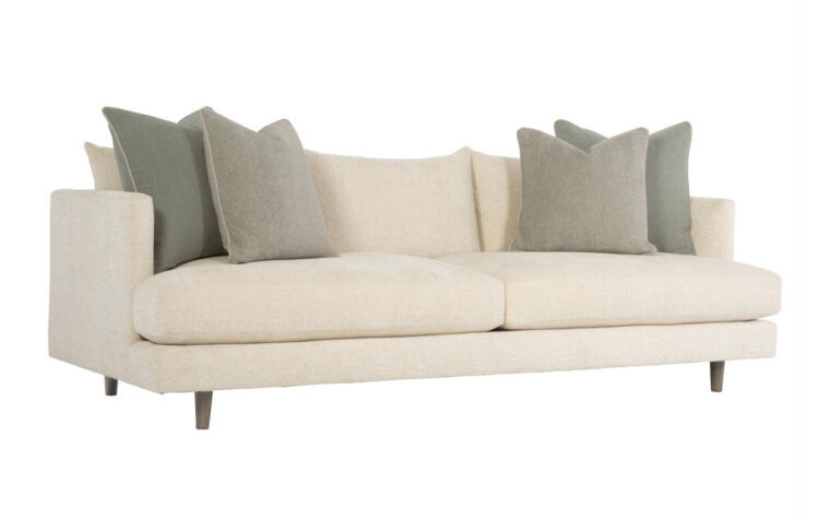 Angled view of the Colette stylish modern sofa by Bernhardt in cream fabric with two green throw pillows on either side
