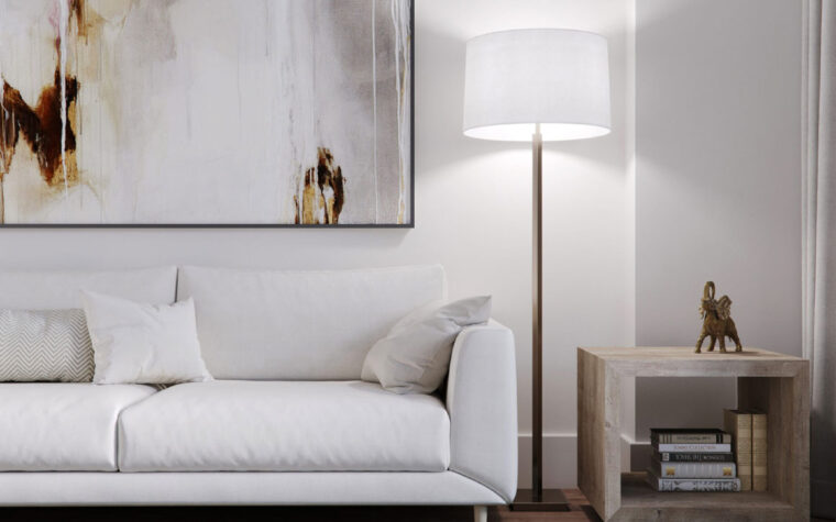 The Sydney brass floor lamp with an off-white linen shade in the corner of a living room beside a white sofa