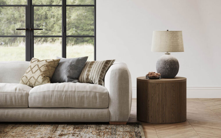 A modern table lamp with a beige linen lamp shade on a side table in a living room setting.
