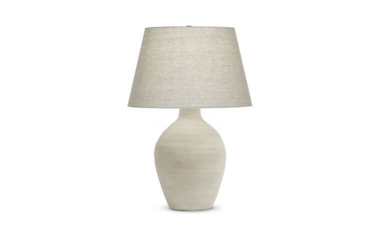 A organic table lamp with a cream ceramic base and a beige linen lamp shade.