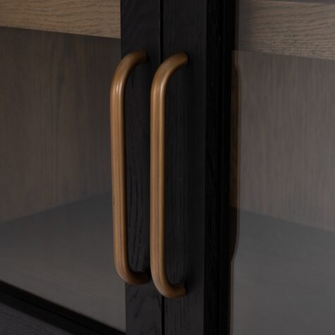A detail shot of the tolle arched bookcase by Four Hands showcasing the antique brass hardware and clear glass doors. 