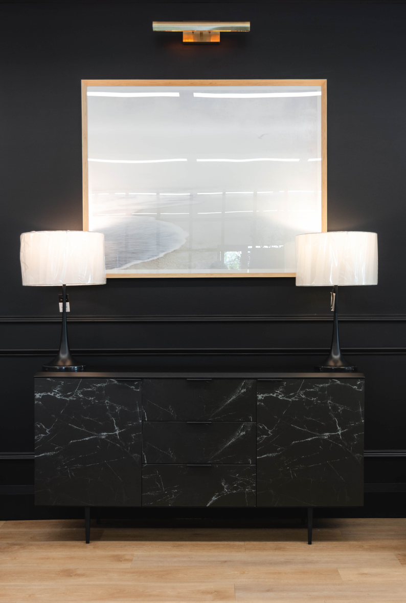 A modern sideboard in Chervin Furniture & Designs' Elmira Showroom with 2 lamps on top and wall art.