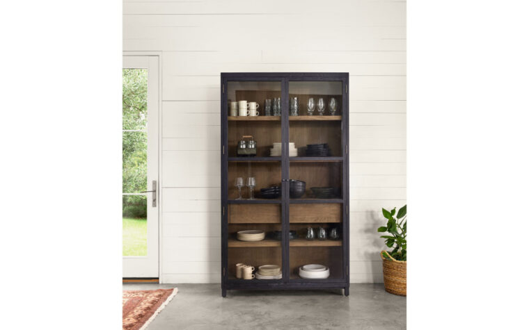 black cabinet with white oak interior and glass doors in a white room with concrete floors
