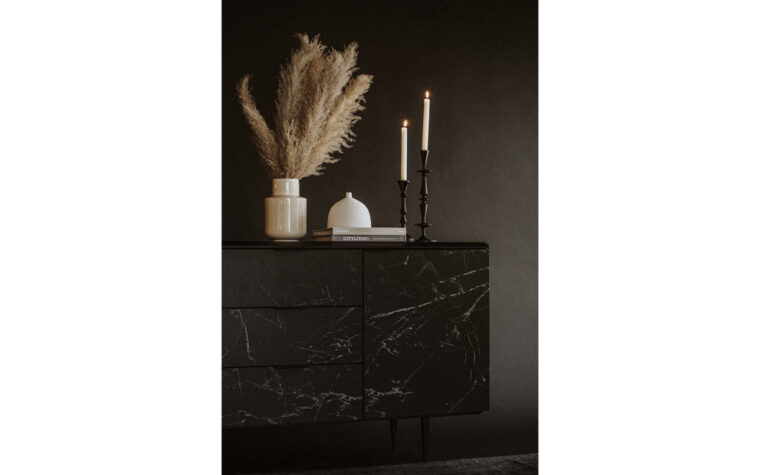 A modern sideboard with black and white ceramic cladding by Moe's Home Furniture in a living room setting with decor ontop..