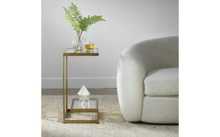 A side view of the musing glass side table with shelf by Uttermost styled beside accent chair.