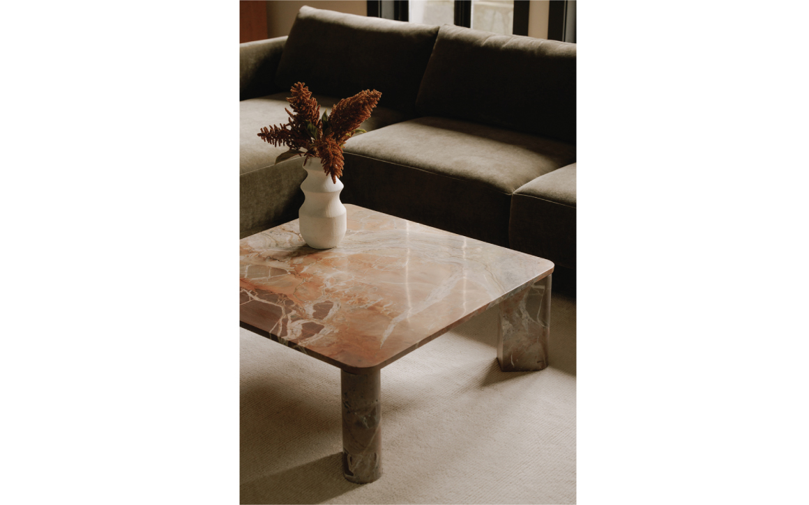 Segment orange marble coffee table by Moe's Home styled in modern living room in front of green sofa.