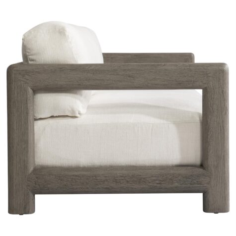 side view of the montaigne outdoor sofa in a weathered grey finish with white cushions with showwood arms and back