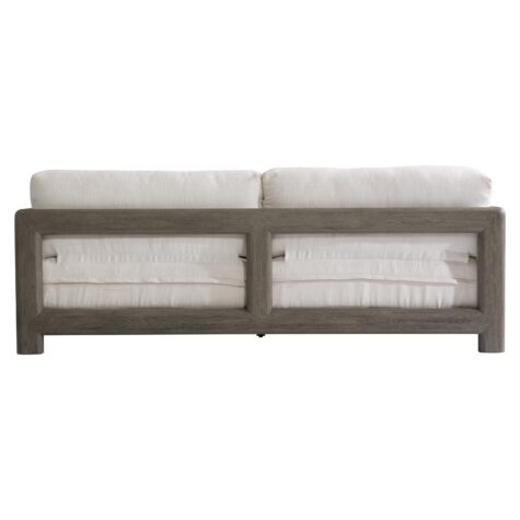 back view of the montaigne outdoor sofa in a weathered grey finish with white cushions with showwood arms and back