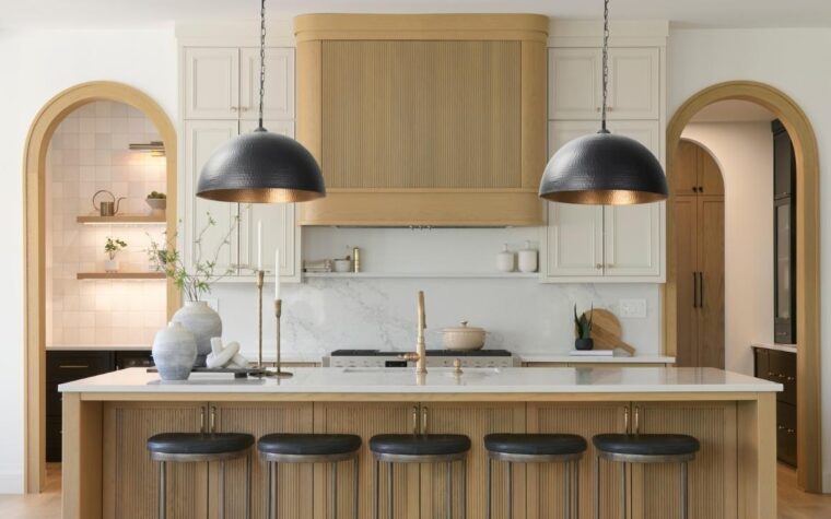 a transitional white and wood kitchen with black and gold hammered pendants